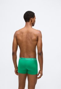 Zöld boxer alsónadrág, szoros illeszkedéssel, fehér "TOMMY HILFIGER" logóval a derékrészen. Sima anyag, minta nélkül.