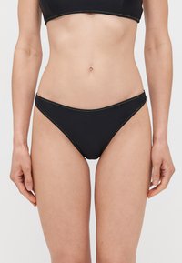 Crni donji dio bikinija s niskim strukom, glatkom teksturom i kontrastnim šavovima. Jednostavan, minimalistički stil.
