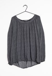 Haut gris à motif chevron avec un large décolleté, des détails froncés et un ourlet élastiqué, suspendu à un crochet noir.