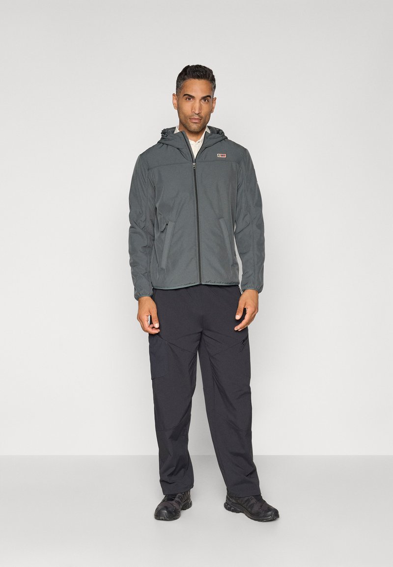 Veste à zip grise avec capuche, présentant un tissu texturé. Portée avec un pantalon cargo noir. La tenue est pratique pour une utilisation en extérieur.