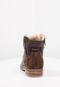 Braune Knöchelstiefel mit Wildleder-Oberfläche, seitlichem Reißverschluss, weichem Fellfutter und einem Logo-Patch. Verfügt über eine strapazierfähige Gummisohle und strukturierte Akzente.