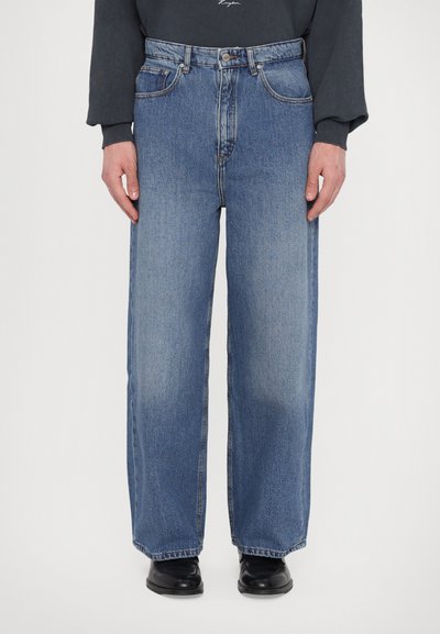 Jeans en denim bleu clair avec une taille haute, des jambes larges et un design classique à cinq poches. Présente une fermeture par bouton et zip à l'avant.