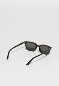 Gafas de sol carey con lentes oscuros, montura cuadrada y material plástico suave. Presentan una marca sutil en la patilla.
