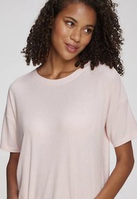 Hele roosa soonikkoes T-särk lühikeste varrukatega ja ümara kaelusega, millel on lõdvestunud lõige ja pehme tekstuur, sobib vabaajaks kandmiseks.