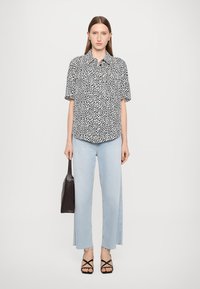 Short-sleeved black and white polka dot shirt paired with light blue wide-leg cropped jeans. Accessories include a black bag and strappy sandals.