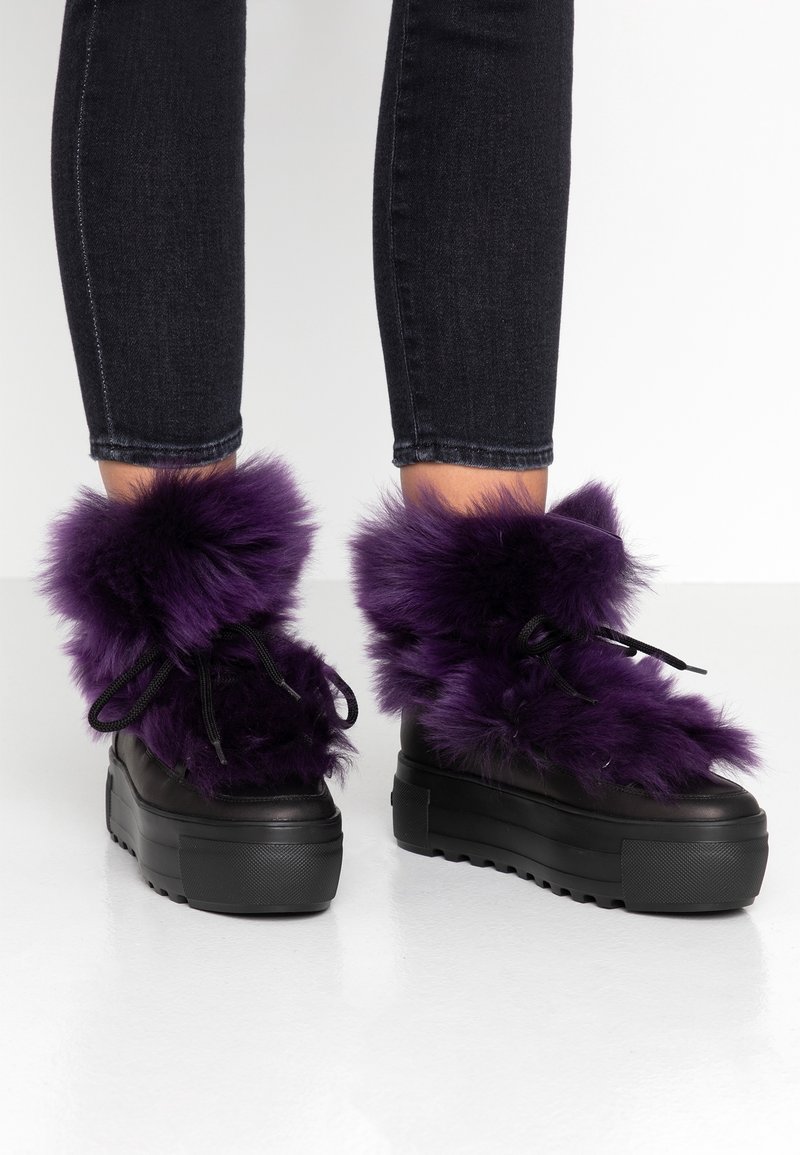 Fialové kožené ankle boty z umělé kožešiny s černými robustními podrážkami a tkaničkami, s chlupatým lemem a hladkým koženým vzhledem.