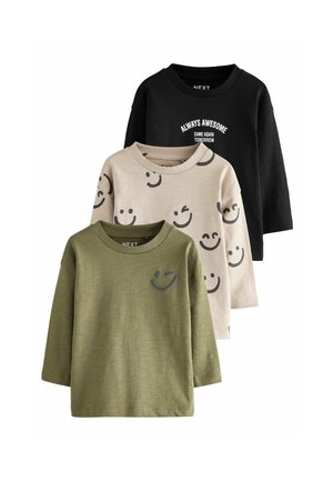 Trois T-shirts à manches longues : noir avec du texte, beige avec des visages souriants et vert olive avec un design de clin d'œil. Tissu en coton, coupe décontractée.