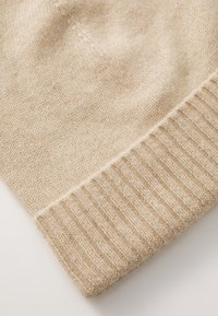 Lichtbeige gebreide stof met een gladde textuur en geribbelde manchetdetails. Aanpasbare flexibiliteit voor comfort en pasvorm.
