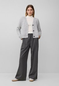Hellgrauer, gestrickter Cardigan mit rundem Ausschnitt und Knopfleiste, kombiniert mit dunkelgrauen, hoch taillierten, weiten Hosen. Strukturiertes Material.
