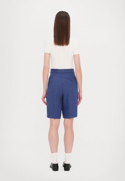 Shorts blue ajustés en tissu texturé, avec une ceinture, une poche arrière et une coupe droite juste au-dessus du genou.