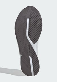 Podeszwa buta z teksturowanej czarnej gumy, z wzorami w zygzak i białą podeszwą środkową z wytłoczonym napisem "ADIDAS" dla lepszej przyczepności i trwałości.