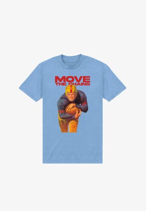Lyseblå T-shirt med en vintage fodboldspiller med gul hjelm, der holder en fodbold, over rød tekst der lyder "MOVE THE CHAINS."