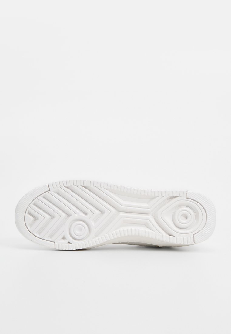 Suela de zapatilla blanca con patrones circulares y en zigzag, superficie texturizada y puntera redondeada. Material de goma suave con agarre blando y flexible.