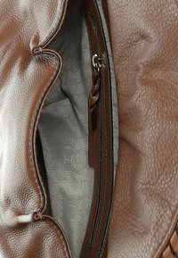 Brązowa skórzana torebka z fakturowaną powierzchnią, z wewnętrzną kieszenią na zamek i szarą wzorzystą podszewką. Detale z ozdobnym przeszyciem.