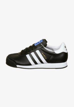 Black leather sneaker with white stripes, cushioned collar, and rubber sole. Features gold "Samoa" text and blue logo tag on the tongue.