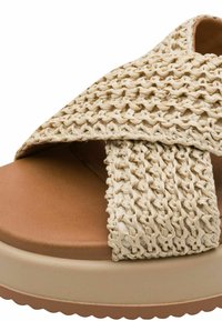 Beżowa sandałka z plecionego materiału przypominającego słomę, z grubą, jasnobrązową platformą i skrzyżowanymi paskami. Gładka faktura i zaokrąglone krawędzie podkreślają design.
