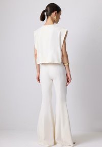 White, cropped top with cap sleeves paired with flared, full-length pants. Smooth fabric and clean lines create a cohesive look.