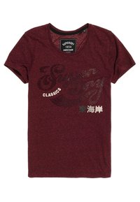 Camiseta burdeos de tejido suave con cuello redondo y mangas cortas. El diseño frontal incluye letras metálicas y acentos.