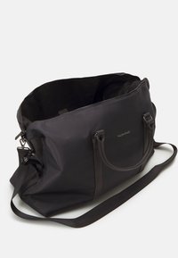 Sac de sport en nylon noir avec deux poignées supérieures et une sangle d'épaule réglable, doté d'une fermeture éclair et d'un logo en relief sur le devant.