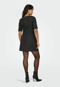 Korte mouwen, donkergrijze jurk met een aansluitende taille en een uitlopende rok. Gecombineerd met zwarte hoge enkellaarsjes en doorschijnende panty's.