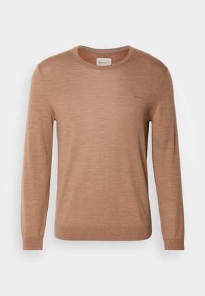 Kerge materjaliga pruun pikkade varrukatega sviiter, millel on ümmargune krae ja peene logo detail rinnal. Sile tekstuur.