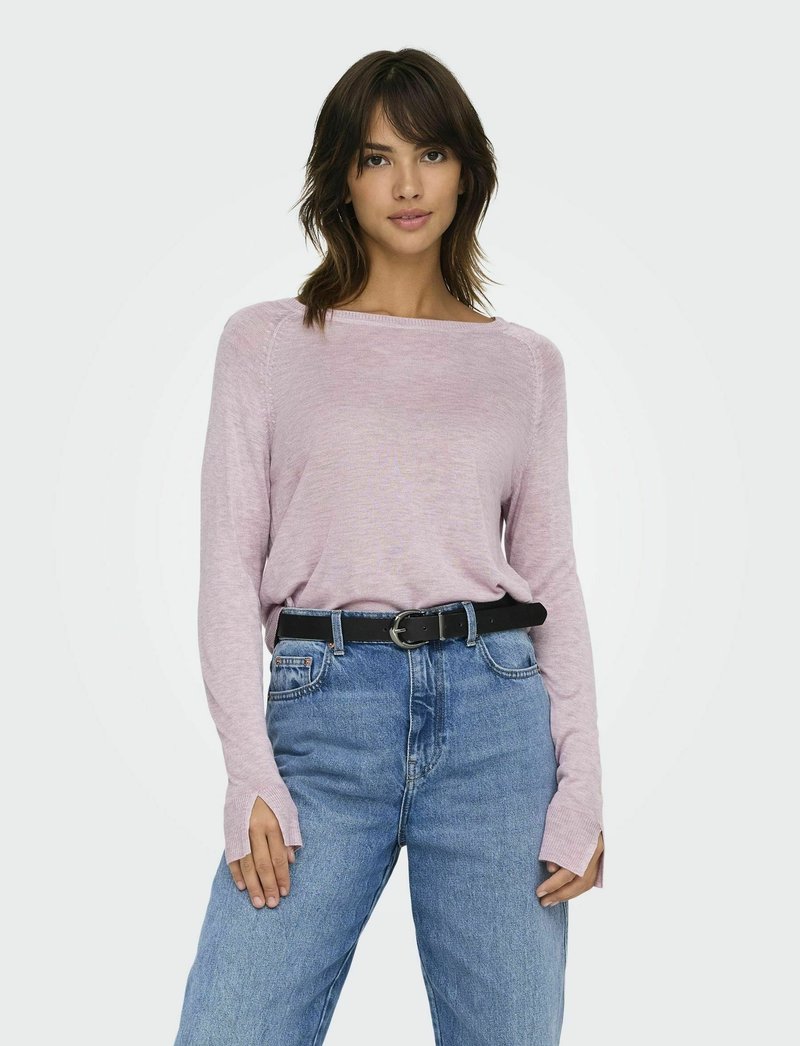 Lichtroze langemouwen top met een boot halslijn en geribbelde details, gedragen met hoge taille blauwe jeans en een zwarte riem met een zilveren gesp.