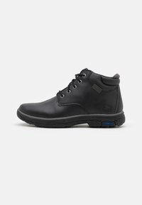 Botas de cuero negro hasta el tobillo con diseño de cordones, cuello acolchado y suela de goma. Presenta detalles de emblema y acentos grises en la lengüeta.