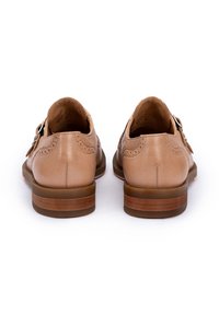 Braune Lederschuhe mit Broguemuster, doppelten Schnallen und einem gestapelten braunen Absatz. Glatte Textur mit detaillierten Steppnähten.