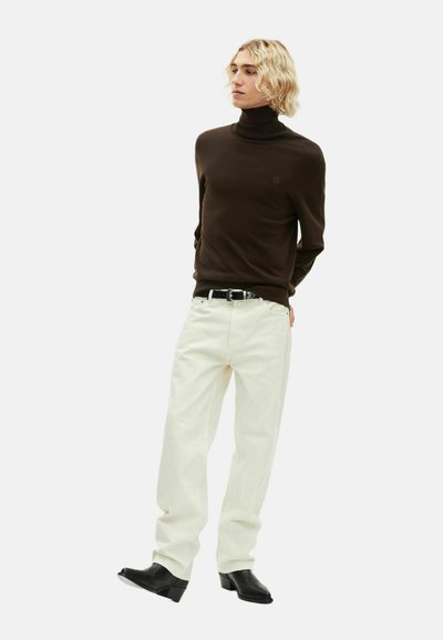 Brauner Rollkragenpullover, crèmefarbene weit geschnittene Hose und schwarze Stiefel mit Absatz. Schlichtes Design mit einem Logo auf dem Pullover. Glatte Textur.