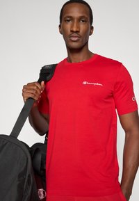 Κόκκινο κοντομάνικο μπλουζάκι από βαμβάκι, με λευκό λογότυπο «Champion» στο στήθος και ετικέτα λογότυπου στο μανίκι.