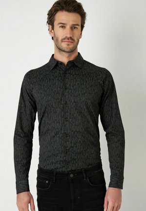 Langarm schwarzes Hemd mit strukturiertem Muster, Knopfverschluss vorne, klassischem Kragen und schmaler Passform, kombiniert mit dunklen Jeans.