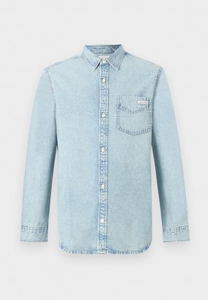 Lys blå denimskjorte med lange ermer, knapper foran, enkelt brystlomme med Calvin Klein-logo, og spiss krage.