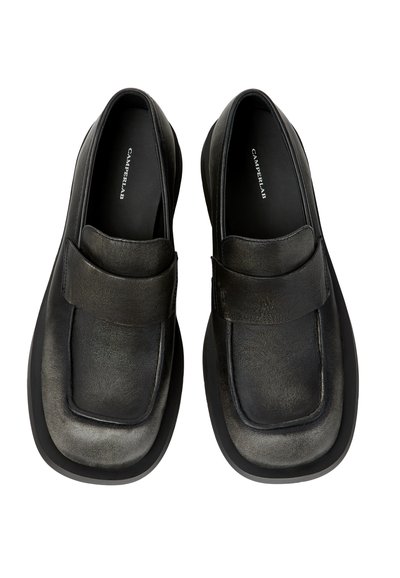 Mocassins slip-on en cuir noir avec une large bride sur le dessus, bout carré et semelle épaisse, marqués Camperlab sur la semelle intérieure.
