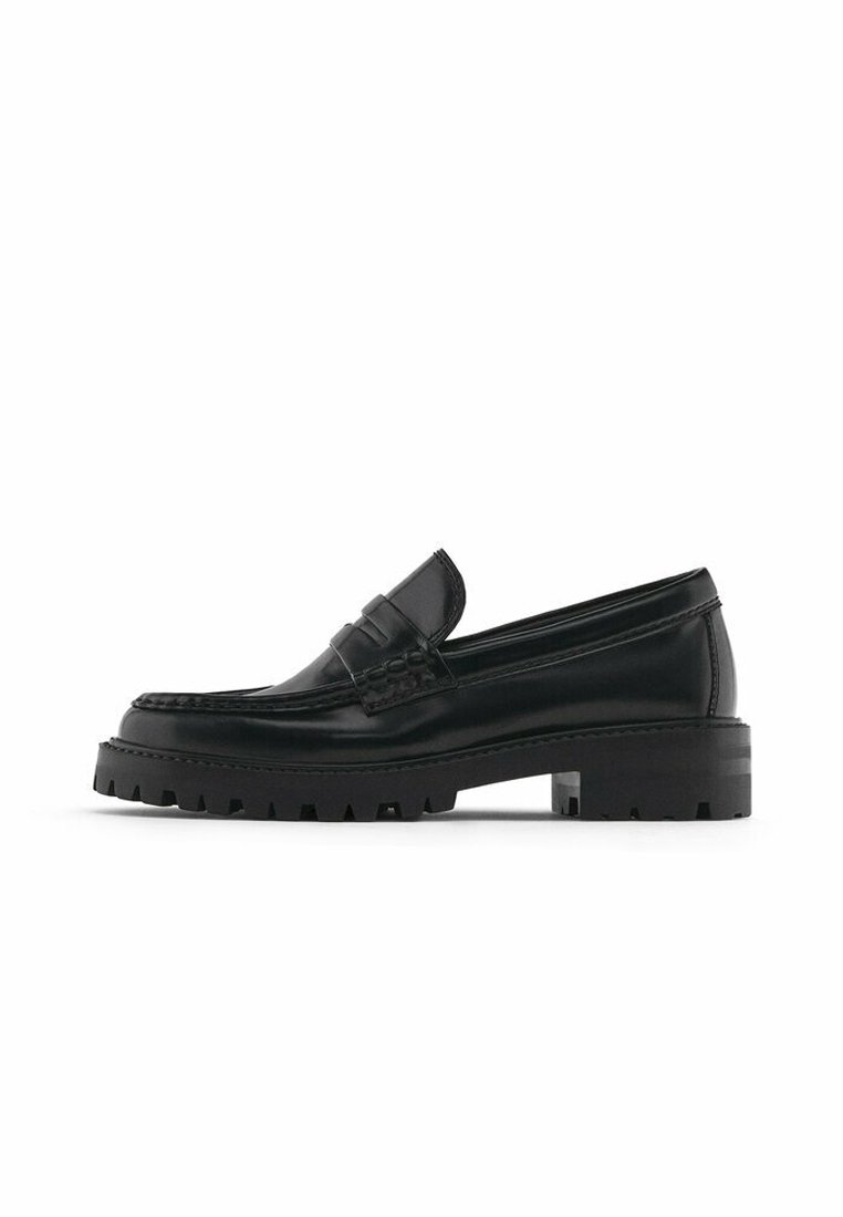 Mocassin à penny en cuir noir avec semelle crantée épaisse et talon bas, présenté de profil sur fond blanc.