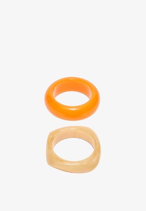 Deux bagues en résine, l'une lisse et ronde orange vif, l'autre carrée avec des bords arrondis beige.