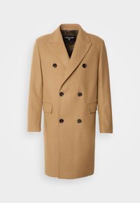 Cappotto doppiopetto color cammello in misto lana. Presenta grandi bottoni neri, rever con intaglio e tasche laterali. Texture liscia, taglio dritto.