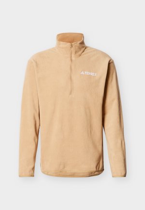 Μπεζ φλις μπλούζα με μακριά μανίκια, φερμουάρ τετάρτου μήκους και ψηλό γιακά, με λευκό λογότυπο "TERREX" στο αριστερό στήθος.