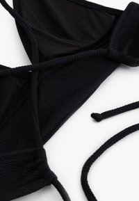 Czarny biustonosz bikini z trójkątnymi miseczkami, teksturowanym materiałem, regulowanymi paskami i cienkimi ramiączkami. Posiada gładkie wykończenie i minimalistyczny design.