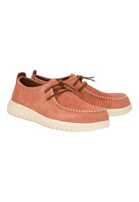 Zapatos de ante en un suave color coral con cordones marrones. Presentan costuras blancas y una suela de goma crema con una superficie texturizada y antideslizante.