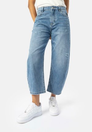 Light blue denim wide-legged jeans with distressed details. Features a high waist and raw hem, paired with white sneakers.