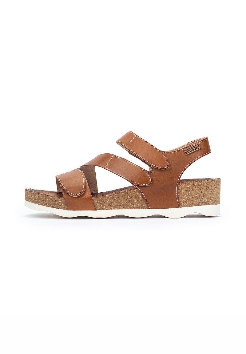 Sandalias de cuero marrón con correas de Velcro ajustables, plantilla de corcho y suela de goma blanca. Presentan un diseño moderno abierto y costuras reforzadas.