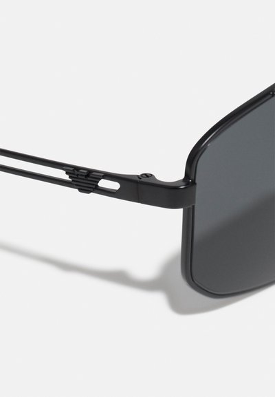 Occhiali da sole neri con montatura rettangolare, finitura matt e lenti grigie. Presentano un design elegante delle aste con dettagli a taglio.