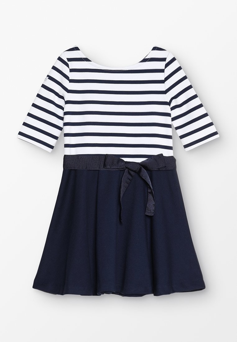 Robe fille avec haut rayé horizontal bleu marine et blanc, manches trois-quarts, jupe unie bleu marine et ceinture en tissu bleu marine nouée en nœud à la taille.