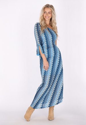 Rochie maxi de culoare albastră cu motive în valuri. Mânici trei sferturi cu fante laterale, bordură contrastantă de culoare turcoaz și țesătură moale, texturată.