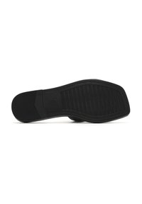 Sole di scarpa in gomma nera con un motivo testurizzato per la presa. Forma curvata con tacco piatto e una transizione liscia alla sezione superiore.
