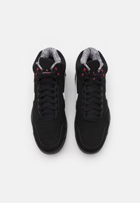 Černé sportovní boty s nubukovým vnějším pláštěm, síťovaným jazykem a bílými akcenty. Mezi výrazné rysy patří vzorovaná podšívka a červené očky.