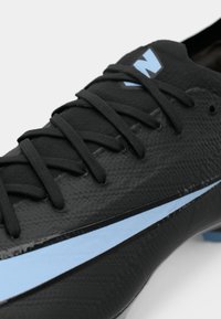 Black soccer cleat with textured finish, flat black laces, light blue accents, and a logo on the tongue; streamlined design for performance.