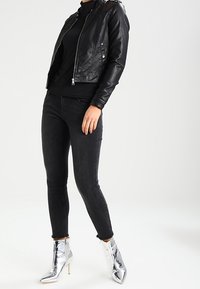 Sort læder bikerjakke med sølvhardware, parret med sorte skinny jeans og metalliske sølvankelstøvler med spidse tæer.