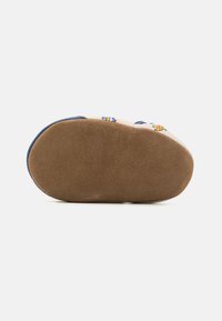 Suela de zapato con una superficie texturada de color marrón claro, con un borde azul y estampados de animales coloridos en la parte superior. Forma redondeada para mayor comodidad.