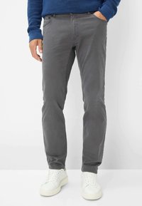 Grijze katoenen broek, slim fit, met zijzakken. Gepaard met witte sneakers, met een gladde textuur en eenvoudig ontwerp.